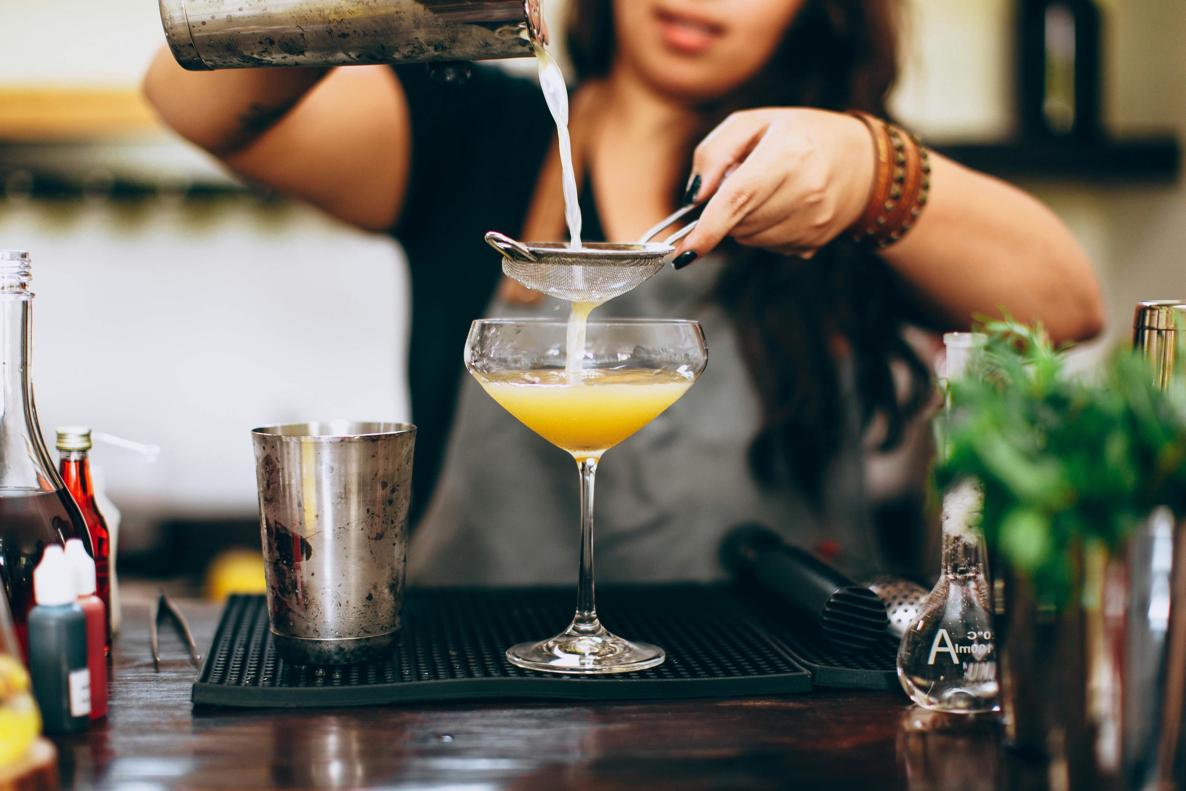 Bartender a coar um cocktail para uma taça