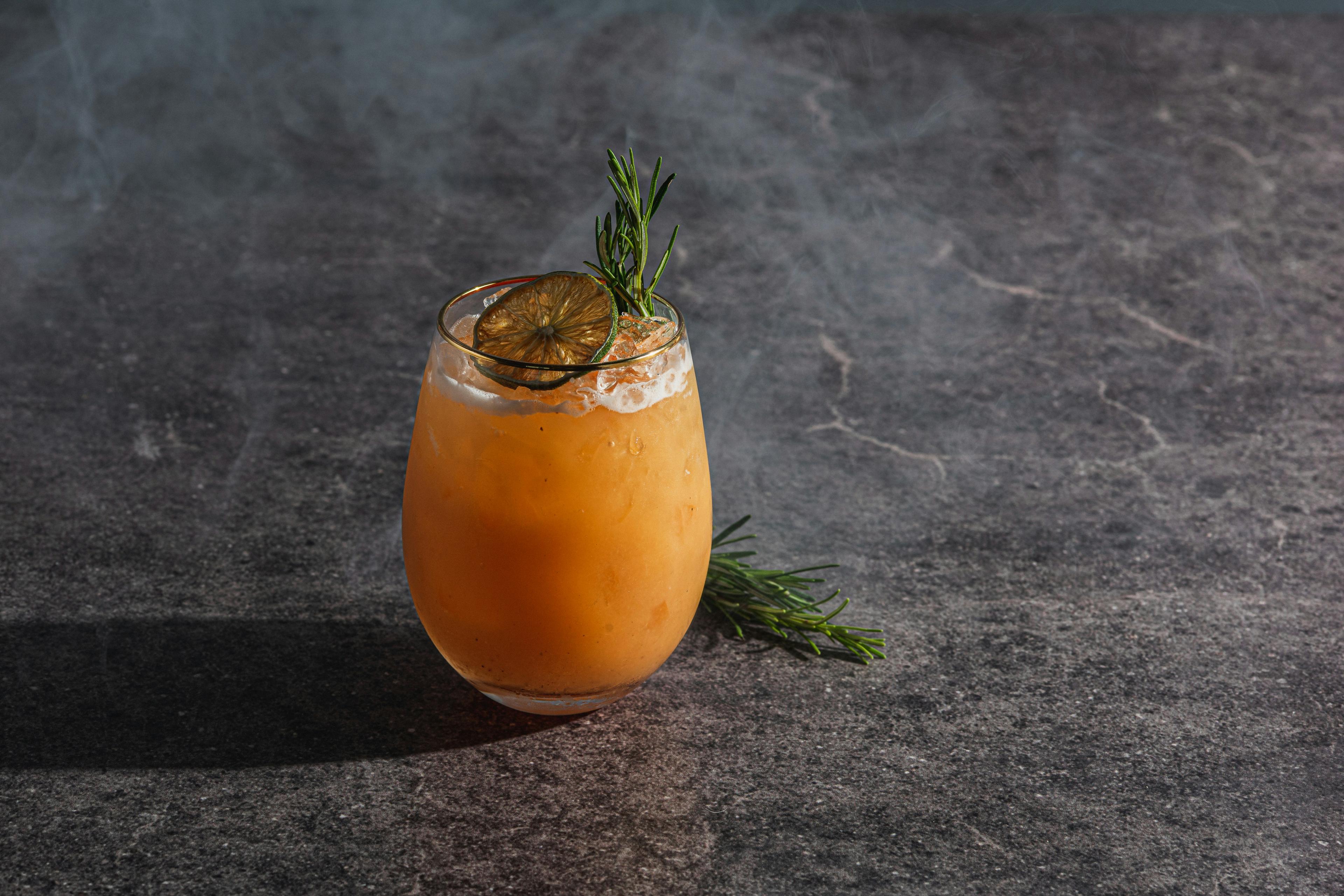 Cocktail de laranja decorado com alecrim